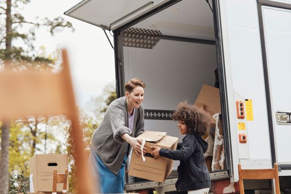 Woman handing a child a moving box | Source: Getty Images