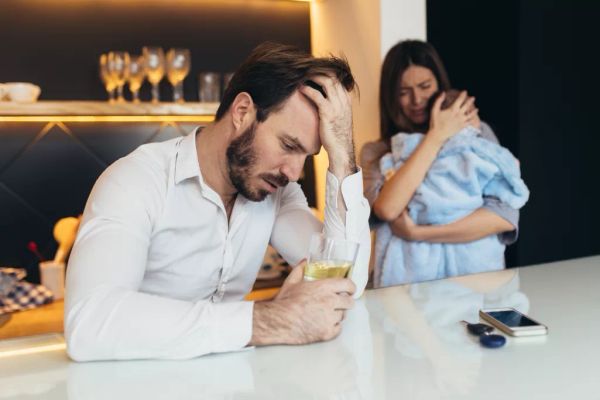 A woman with a child standing behind a depressed man | Source: Shutterstock