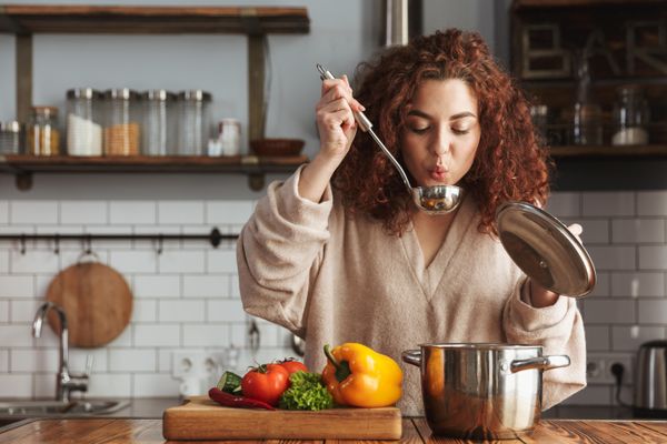 A woman tasting the food she has cooked