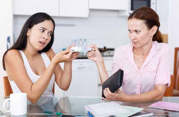 A woman giving a girl money. | Source: Shutterstock